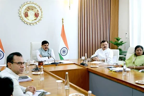 मुख्यमंत्री निवास के बैठक कक्ष में झंडों के बीच अधिकारी मेज पर बैठे हैं